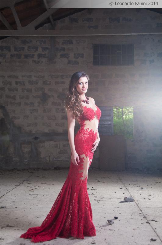 modella In posa in piedi con abito rosso, in un deposito abbandonato