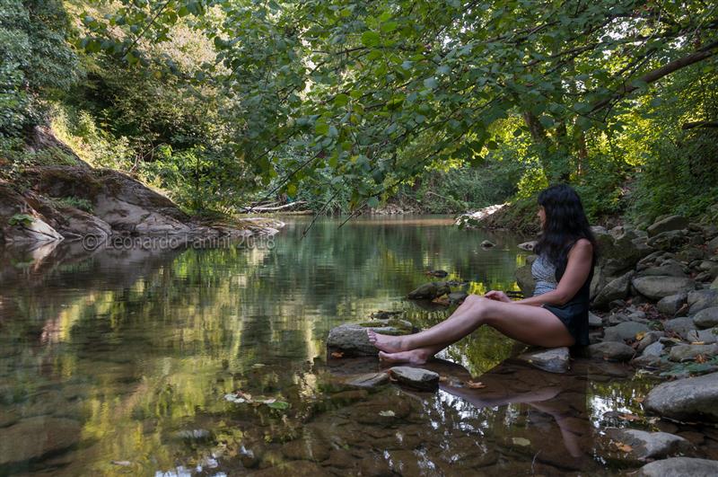 Ragazza seduta graziosamente su una rocca lungo l